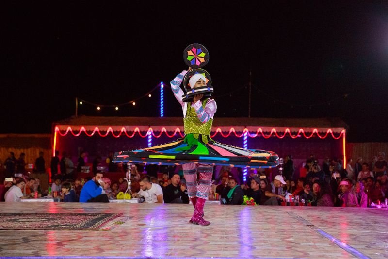 tourists watching tanoura dance performance in emirates desert safari dubai