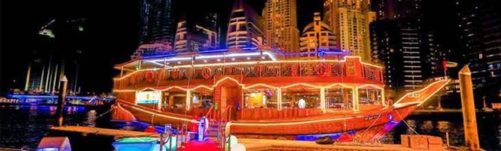 Guests enjoying a gourmet dinner on the deck of a dhow boat, with the Dubai skyline in the background.