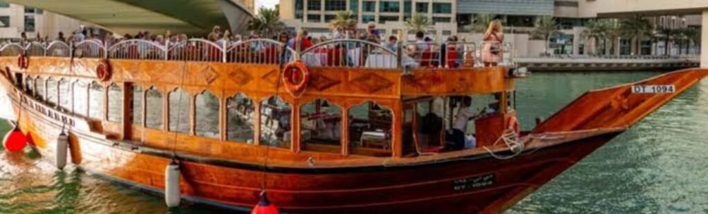 Marina Dhow cruise boat illuminated at night on Dubai's waterfront.