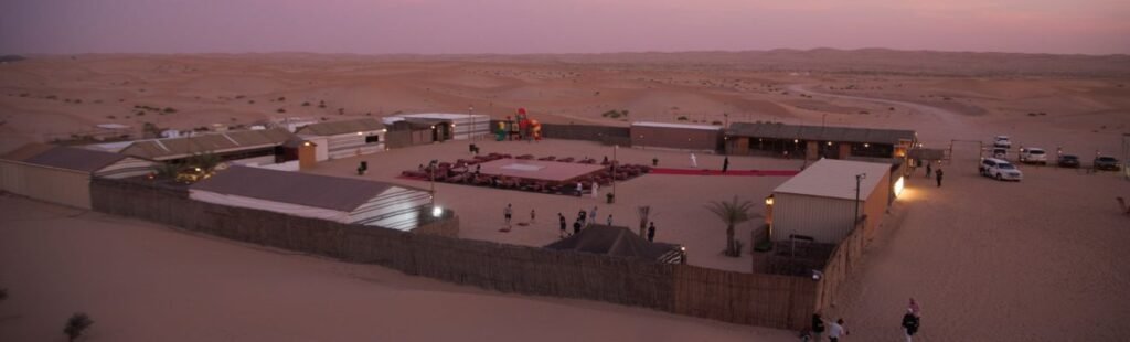 Guests sandboarding down a dune in Dubai's desert.