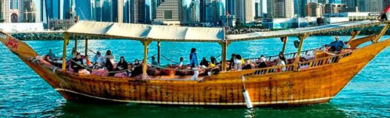 Marina Dhow Cruise sailing along Dubai's waterfront at sunset.