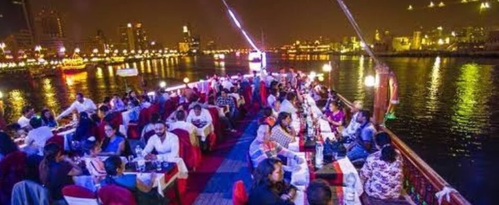 Tour Dubai Dhow Cruise sailing against Dubai skyline at sunset.