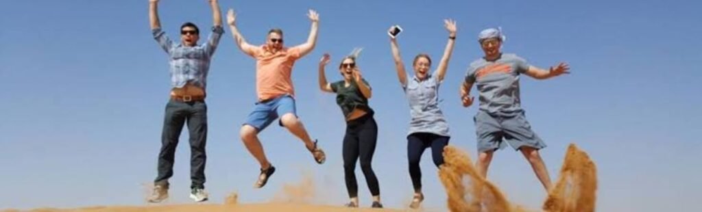 Guests sandboarding down a dune in Dubai's desert.