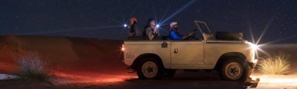 Silhouettes of camels against a moonlit desert sky.