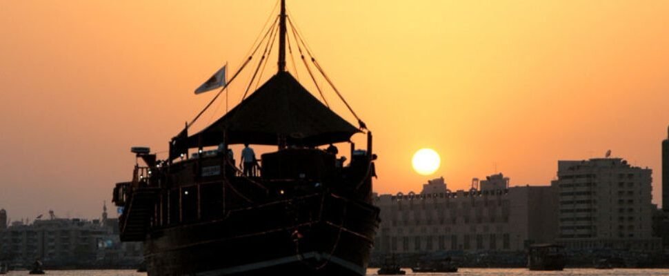 Dhow Cruise sailing on Dubai Creek at sunset.