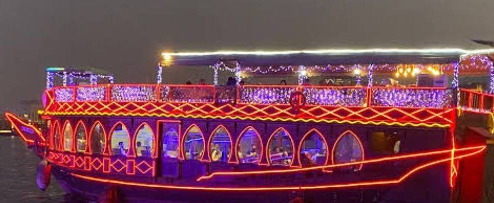 Creek Dinner Cruise with Dubai skyline at night.