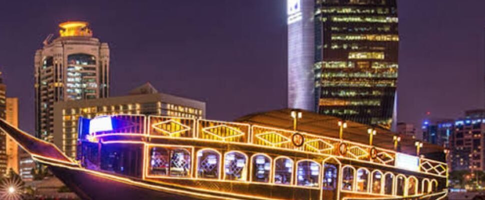 Dhow Cruise Marina illuminated at night with Dubai skyline.