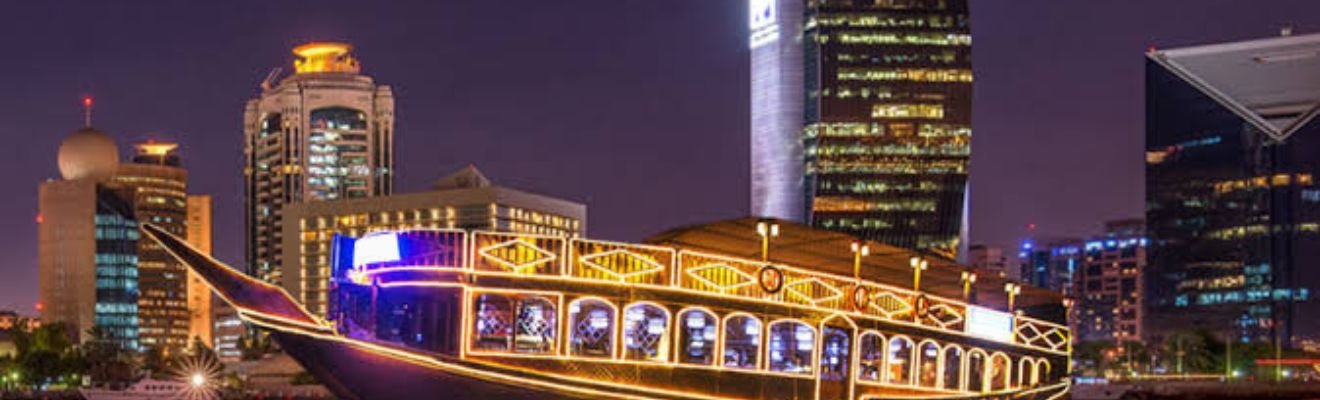 Dhow Cruise Marina illuminated at night with Dubai skyline.