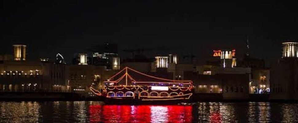 Traditional dhow boat sailing on Dubai's waters at sunset.