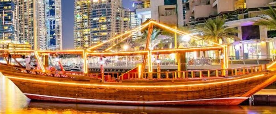 Creek Dhow Cruise sailing on Dubai Creek at sunset.