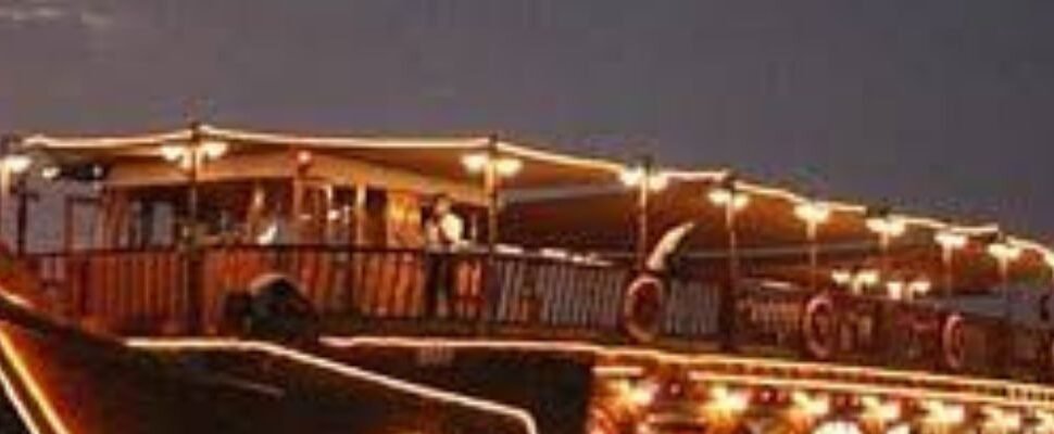 A beautifully lit dhow boat cruising Dubai's waters at sunset.