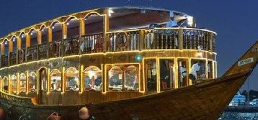 Creek Dhow Dinner Cruise › Forever Tourism LLC Dhow boat cruising along Dubai Creek at sunset.