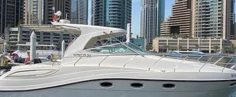 Luxury yacht cruising through Dubai Marina at dusk.