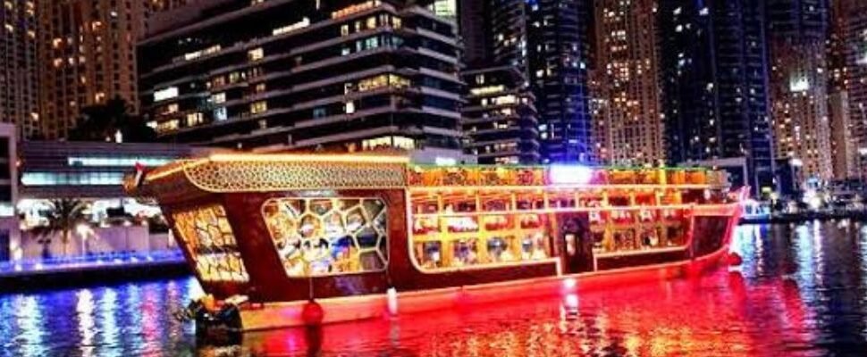 Dhow cruise boat sailing through Dubai Marina at dusk.