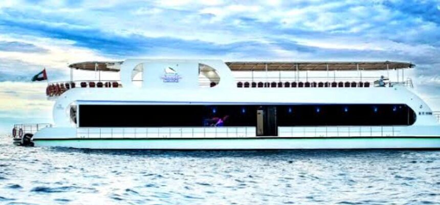 A luxury dhow cruise illuminated against Dubai's skyline at night.