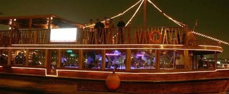 A luxury dhow cruising along Dubai Water Canal at dusk.