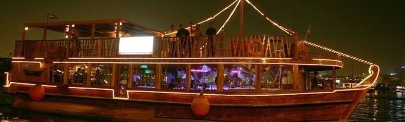 A luxury dhow cruising along Dubai Water Canal at dusk.