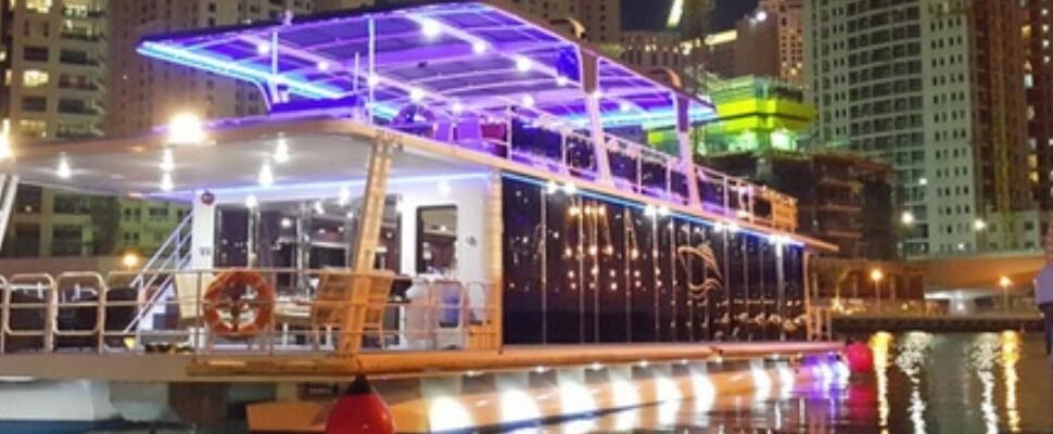 Traditional dhow boat cruising Dubai Marina at twilight.