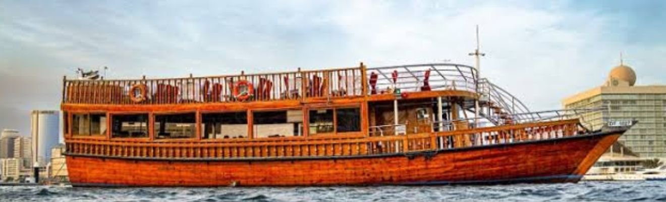 Traditional wooden dhow sailing in Dubai Marina at sunset.