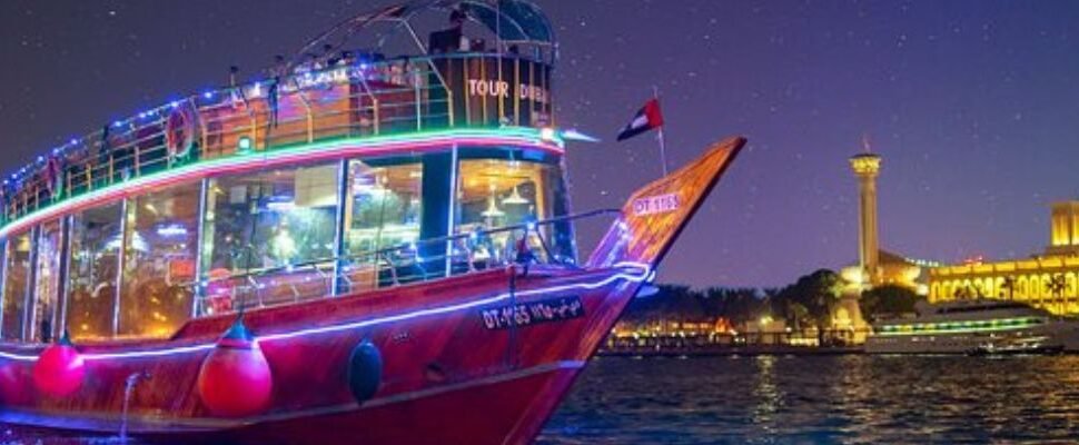 Traditional dhow boat sailing through Dubai Canal at sunset.