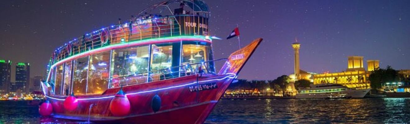 Traditional dhow boat sailing through Dubai Canal at sunset.