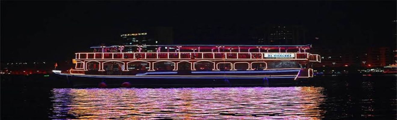 Traditional dhow boat cruising along Dubai Creek at twilight.