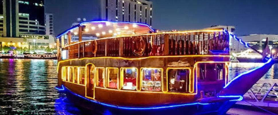 Traditional dhow cruising Dubai's waterfront at sunset.