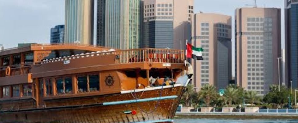 Dhow cruise sailing on Dubai Creek with city lights in the background.