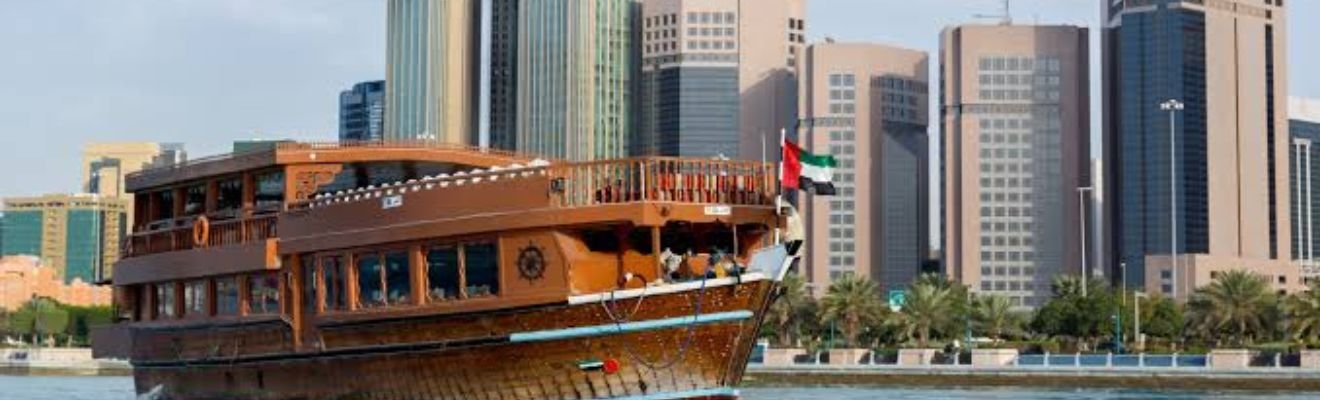 Dhow cruise sailing on Dubai Creek with city lights in the background.