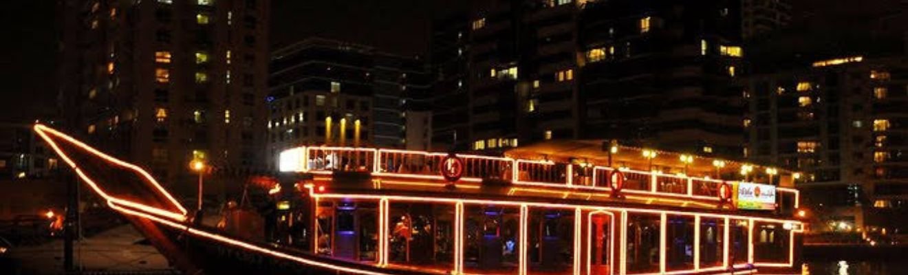 A dhow boat illuminated at night, cruising through Dhow Cruise Dubai Marina Cost: The Best Kept Secret!.