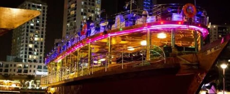 Traditional dhow boat cruising under Dubai Marina's night lights.