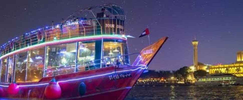 Dubai Marina lit up at night with a dhow cruise in the foreground.