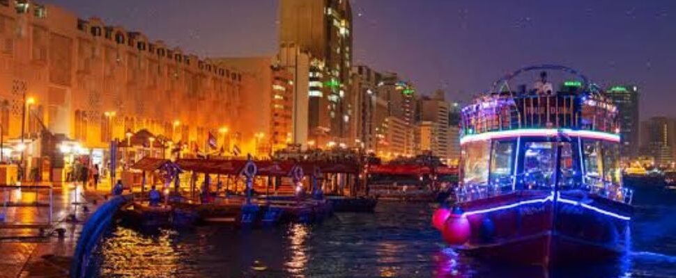 Traditional dhow boat cruising Dubai Creek at sunset.