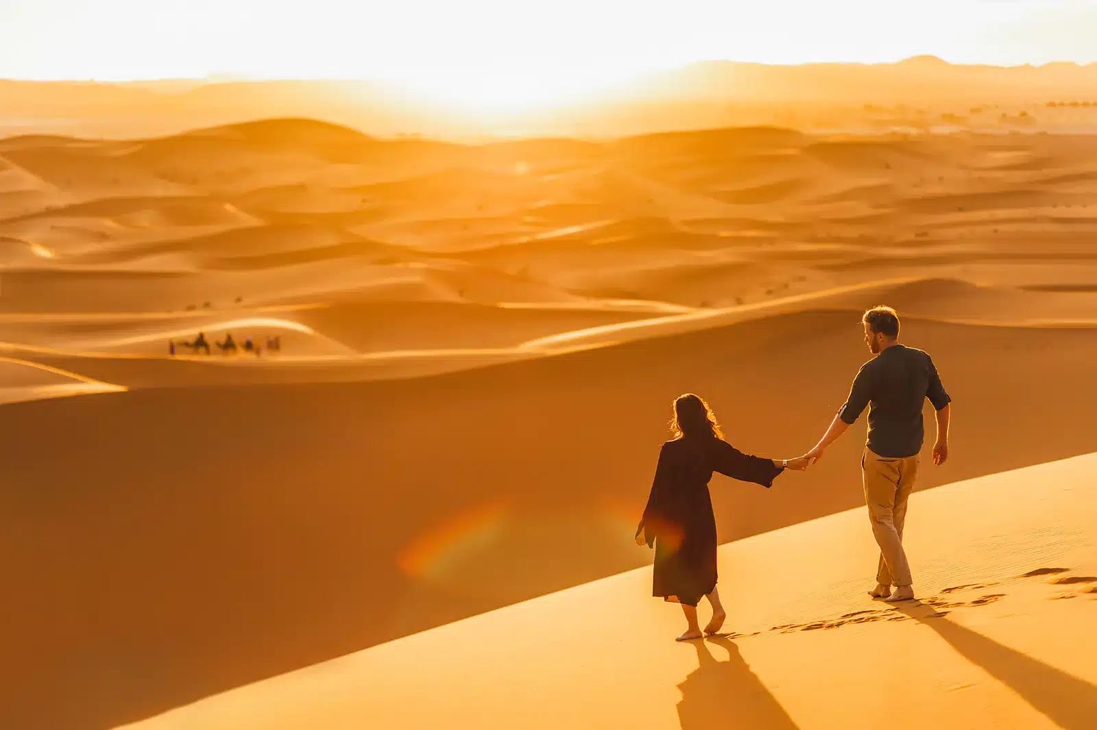 A thrilling Dubai Desert Safari experience featuring a camel ride against the backdrop of golden sand dunes at sunset.