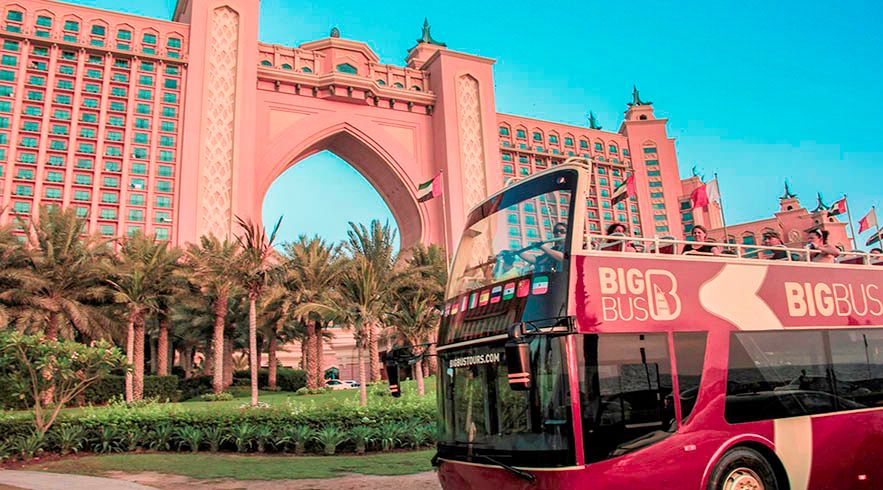 Dubai sightseeing bus driving past city landmarks on a hop-on hop-off red bus tour in Dubai.