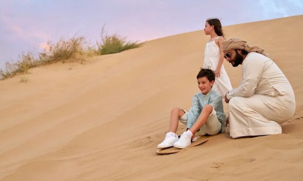 Family enjoying sandboarding adventure during Emirates Desert Safari Dubai.