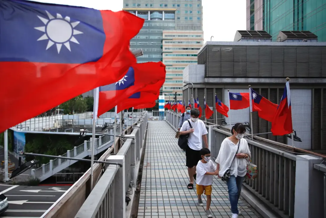People walking past Taiwan flags in Taipei, representing travel opportunities with a Taiwan Visa.