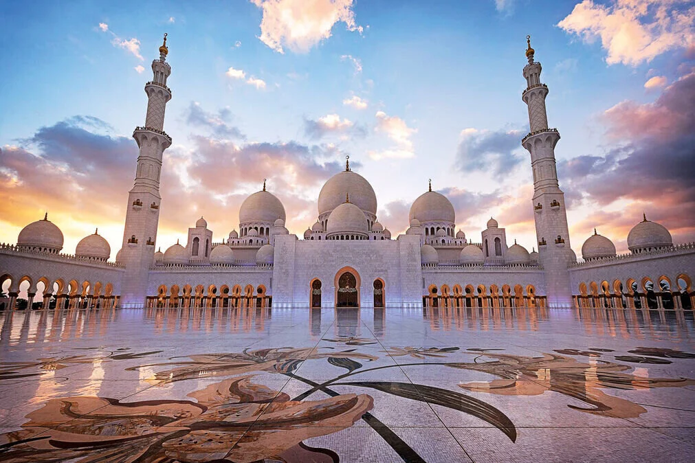 A scenic view of Abu Dhabi featuring the Sheikh Zayed Grand Mosque and the Ferrari World entrance, highlighting a full-day Abu Dhabi City Tour experience.