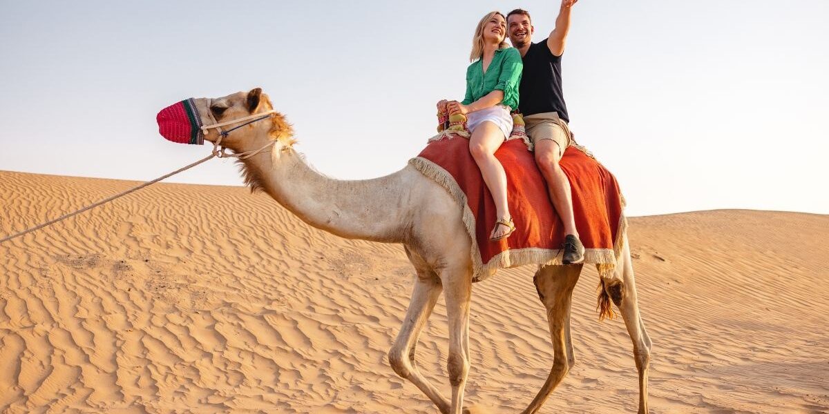 Tourists enjoying Dune Bashing Dubai during an exciting Desert Safari Dubai, with golden sand dunes and exclusive desert safari deals in the backdrop.