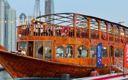 Traditional wooden Dhow Cruise in Dubai sailing through Marina with guests enjoying a dinner cruise and live entertainment.