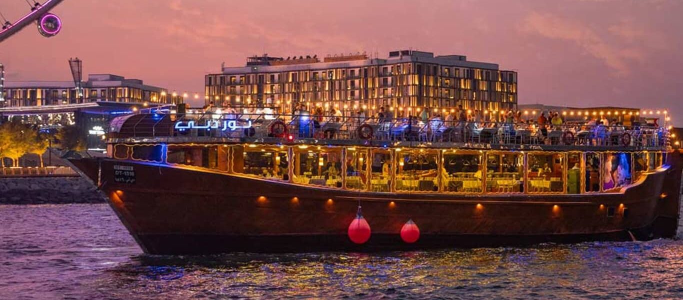 Traditional wooden boat sailing on Dubai Marina at sunset, showcasing the charm of a Dhow Cruise in Dubai with details on ticket price and scenic views.