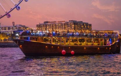 Traditional wooden boat sailing on Dubai Marina at sunset, showcasing the charm of a Dhow Cruise in Dubai with details on ticket price and scenic views.