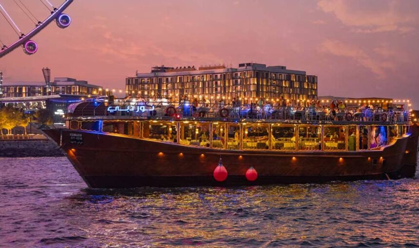 Traditional wooden boat sailing on Dubai Marina at sunset, showcasing the charm of a Dhow Cruise in Dubai with details on ticket price and scenic views.