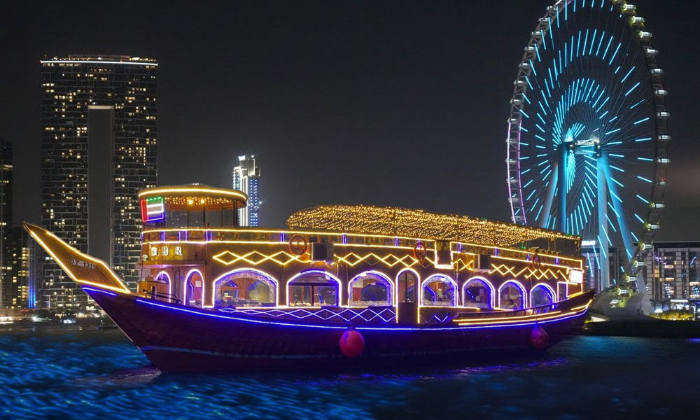 Traditional dhow boat sailing at sunset during the best dhow cruise Dubai at Dhow Cruise Marina, showcasing a scenic view of the skyline.