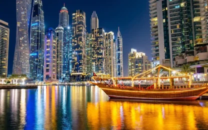 Traditional wooden boat lit up at night during a Dhow Cruise in Dubai, offering a luxurious Dhow Dinner Cruise experience at the Marina.