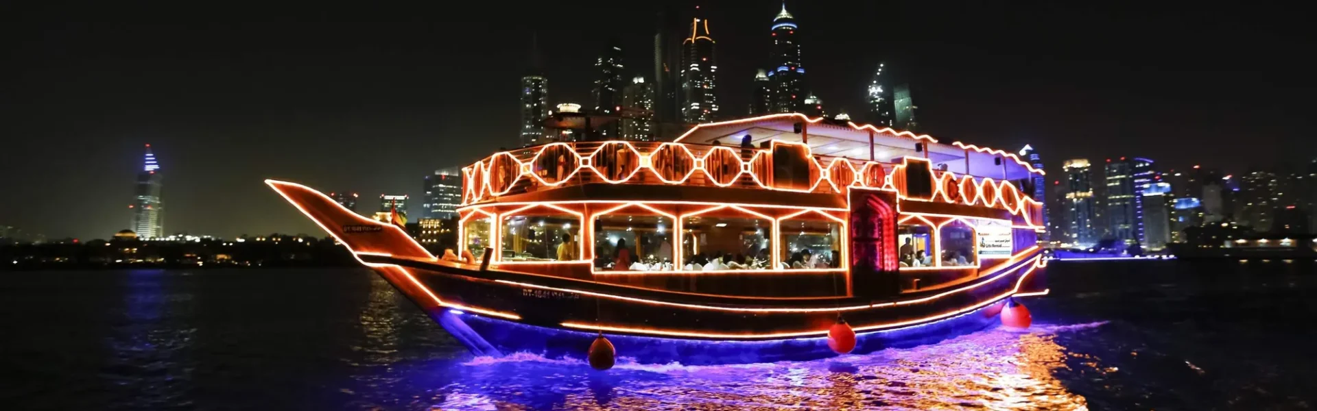 A beautifully lit Dhow Cruise Dubai Marina sailing through the stunning skyline, offering a dinner dhow cruise Dubai Marina experience with gourmet dining and entertainment. Enjoy the best dhow cruise Dubai Marina Dubai under the shimmering city lights.