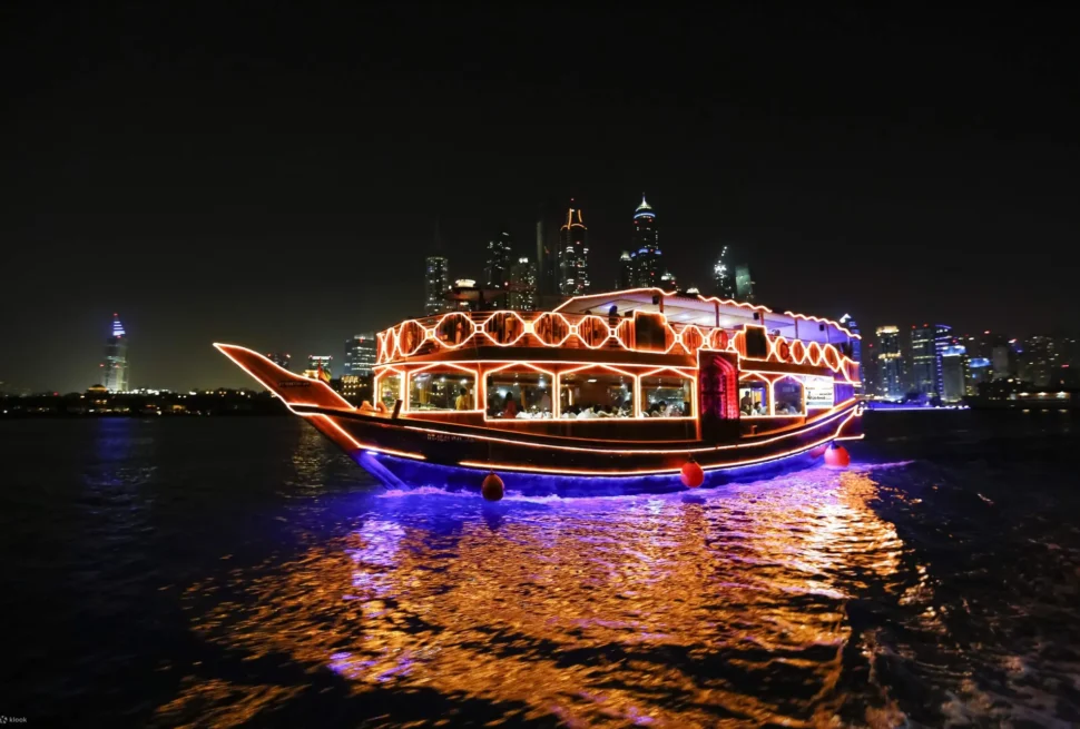 A beautifully lit Dhow Cruise Dubai Marina sailing through the stunning skyline, offering a dinner dhow cruise Dubai Marina experience with gourmet dining and entertainment. Enjoy the best dhow cruise Dubai Marina Dubai under the shimmering city lights.