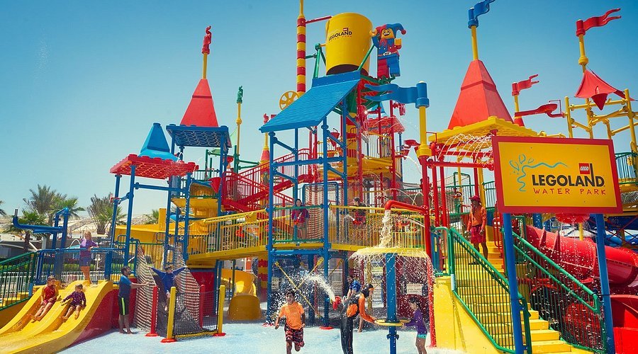 Colorful entrance of Legoland® Dubai theme park with happy families, showing Legoland opening hours, timings, and ticketing information for visitors.