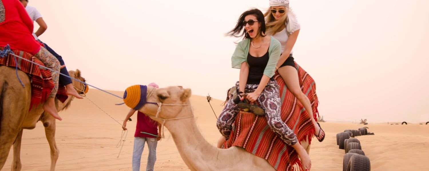 Tourists enjoying dune bashing during the best desert safari in Dubai, with desert safari Dubai booking details and safari timings.