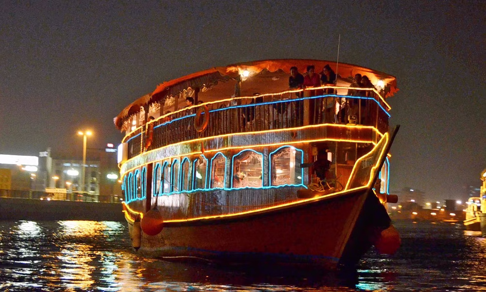 Traditional wooden boat sailing during a Dubai Creek Dhow Cruise with city skyline views – a classic dhow cruise Dubai experience.